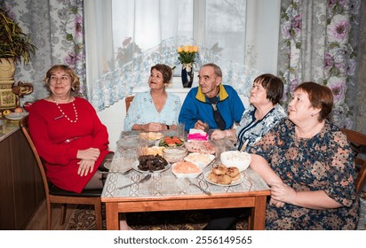 Family and senior friends eating together and watching tv show together at home - Powered by Shutterstock