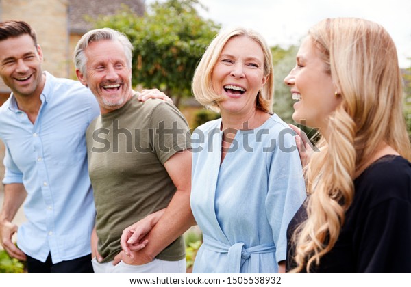 Family With Senior Parents And Adult
Offspring Walking And Talking In Garden
Together
