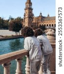 A family in Seville, surrounded by vibrant Andalusian architecture, ornate ceramic tiles, and the lush greenery of a sunlit plaza. 