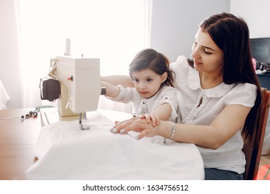 Family with a sewing machine. Woman working at home. Mother with a daughter