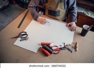 In A Family Shoe Shop A Young Apprentice Works With Paper To Create A Pattern For Shoes.