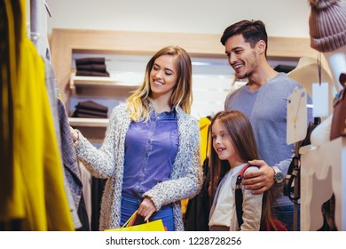 Family Shopping For Clothes And Looking Happy