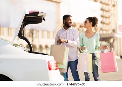 Family Shopping. Happy African Couple Putting Shopper Bags In Car Outdoors On Weekend. Copy Space