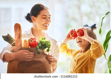 Family shopping. Mother and her daughter are holding grocery shopping bag with vegetables. - Powered by Shutterstock