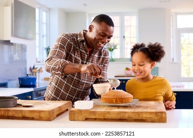 Family Shot With Father And Daughter Baking At Home In Kitchen Decorating Cake With Icing