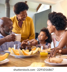 Family Shot With Grandparents Parents And Granddaughter Eating Breakfast Around Table At Home - Powered by Shutterstock