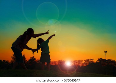 Family Silhouette With Sunset , Family On The Front Of The Sunset In The Sky On A Holiday With Sun Flare On Chatuchak Park At Bangkok City, Thailand. Concept Of Friendly Family.