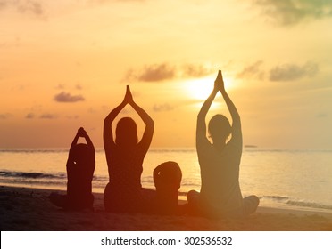 Family Silhouettes Doing Yoga At Sunset Sea