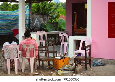 A Family Sit And Eat Their Breakfast In Their Pyjamas Outside Their Pink House.