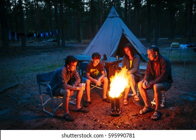 A Family Sits Together At The Camp Fire At A Campsite / Finland, Scandinavia, Europe