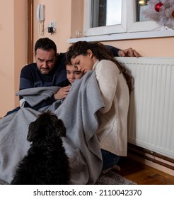 Family Sits Tucked Under The Blanket In Living Room Suffering From Cold Due To Central Heating Problem