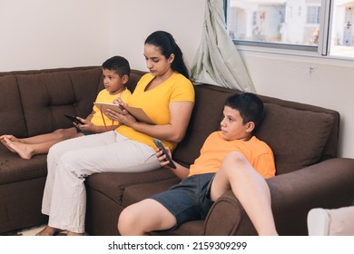 Family Sitting In The Armchair, Mom Checking The Notebook, Son Looking At The Cell Phone