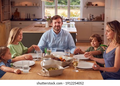 Family Sitting Around Table At Home Joining Hands And Saying Grace Before Meal - Powered by Shutterstock