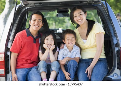 Family Sitting In Back Of Van Smiling