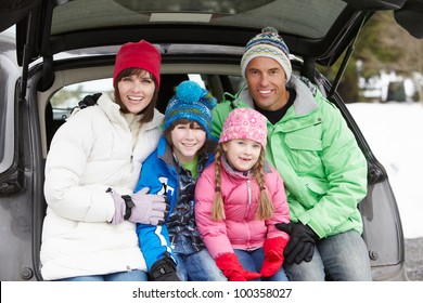 Family Sitting In Boot Of Car Wearing Winter Clothes