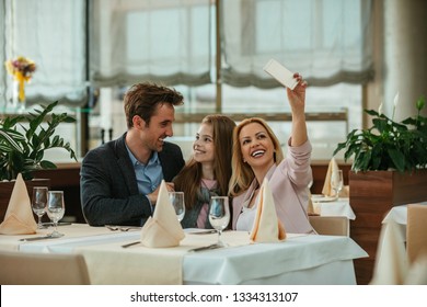 Family Sitting At The Dinning Table In Hotel And Taking Selfie