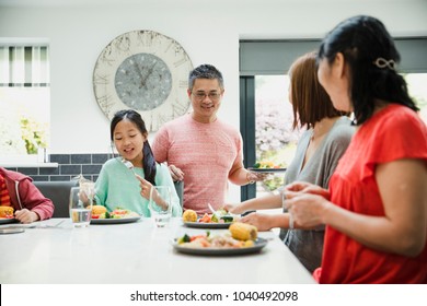 Family Are Sitting Down To Have Their Dinner Together In The Kitchen. They Are Eating A Stir Fry.