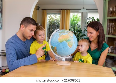 A Family Sitting At A Globe And Is Planning A Trip In The Holidays
