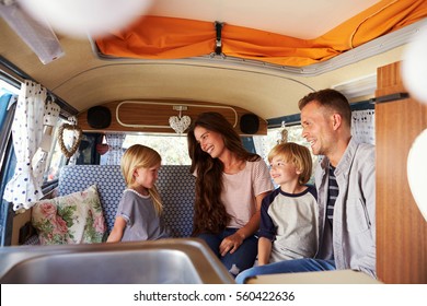 Family Sitting Inside A Camper Van Looking At Each Other