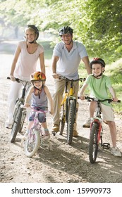 Family Sitting On Bikes On Path Smiling