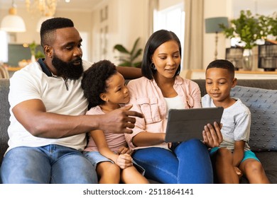 Family sitting on couch, using tablet together, enjoying quality time at home. bonding, technology, living room, leisure, togetherness - Powered by Shutterstock