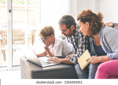 Family Sitting On Sofà At Home Working With Laptop Mother And Father Helping A Young Son Making Homework Wireless Technology Allow To Stay Connected Everywhere Beautiful Familiar Scene Dad Mum And Boy