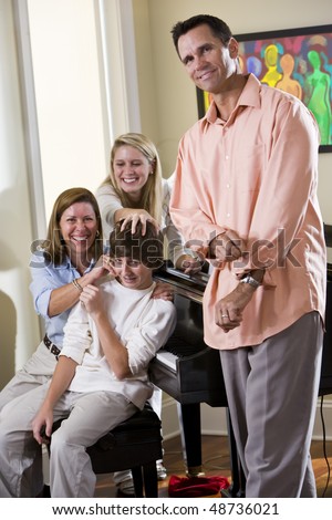 Family sitting on piano bench, mother teasing teenage son