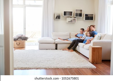 Family Sitting On Sofa At Home Watching TV Together - Powered by Shutterstock