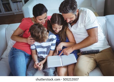 Family sitting on sofa and looking at a photo album at home - Shutterstock ID 505213507