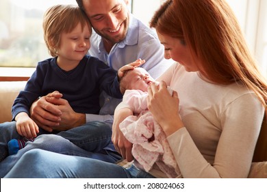 Family Sitting On Sofa With Newborn Baby