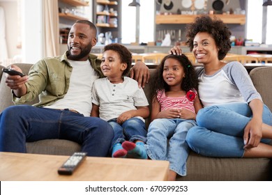 Family Sitting On Sofa In Open Plan Lounge Watching Television - Shutterstock ID 670599253