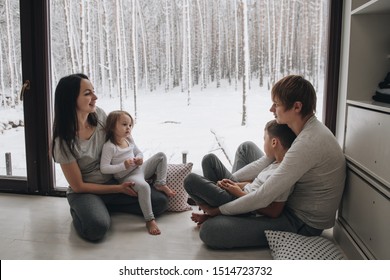 The Family Is Sitting At The Window And Looking At The Winter Forest. Good New Year Spirit. Morning In Pajamas.