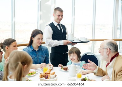 Family Of Six Having Meals In Restaurant With Waiter Near By