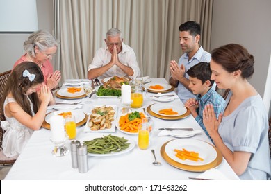 Family of six saying grace before meal at dining table in the house - Powered by Shutterstock