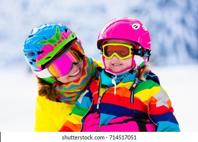 Family Ski Vacation. Group Of Skiers In Swiss Alps Mountains. Mother And Child Skiing In Winter. Parents Teach Kids Alpine Downhill Skiing. Ski Gear And Wear, Safe Helmets.