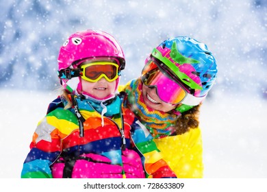 Family Ski Vacation. Group Of Skiers In Swiss Alps Mountains. Mother And Child Skiing In Winter. Parents Teach Kids Alpine Downhill Skiing. Ski Gear And Wear, Safe Helmets.