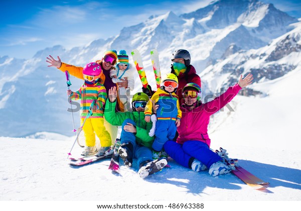 Family ski vacation. Group of skiers in Swiss\
Alps mountains. Adults and young children, teenager and baby skiing\
in winter. Parents teach kids alpine downhill skiing. Ski gear and\
wear, safe helmets.