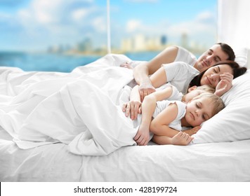 Family sleeping in bed on blurred background