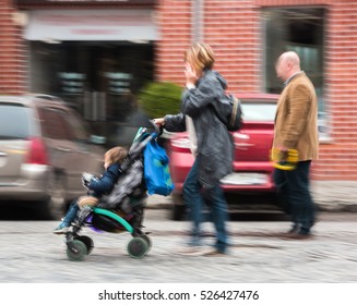 Family with small child in the stroller walking down the street. Intentional motion blur