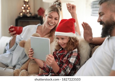 Family With Small Daughter Indoors At Home At Christmas, Having Video Call.