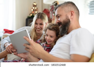 Family With Small Daughter Indoors At Home At Christmas, Having Video Call.