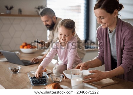 Family with small daughter indoors in kitchen at home, everyday life and home office with child concept.