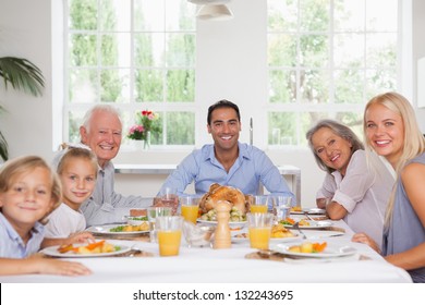 Family Smiling Around The Dinner Table At Thanksgiving