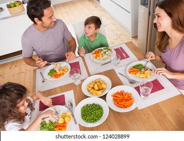 Family Smiling Around A Healthy Meal In Kitchen