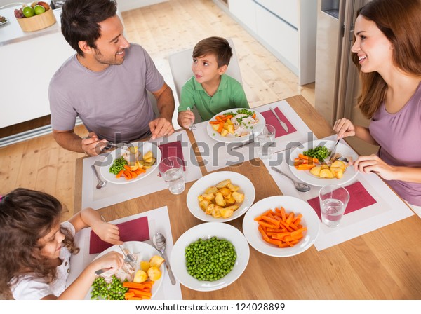 Family smiling\
around a healthy meal in\
kitchen