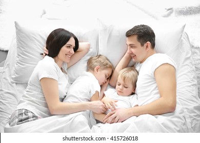Family smiling in bed under blanket, closeup