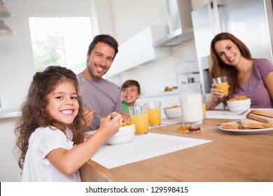 Family Smiling At The Camera At Breakfast In Kitchen