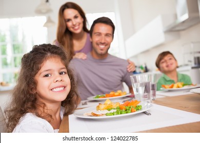 Family Smiling At The Camera At Dinner Table In Kitchen