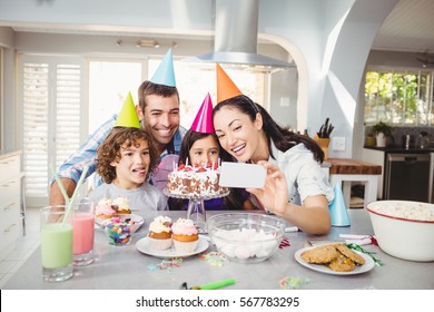 Family Smiling While Taking Selfie During Birthday Celebration At Home