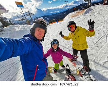 Family Of Snowboarders At Winter Resort In The Mountains 